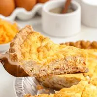 Slice of easy cheddar and bacon quiche in a pie crust.