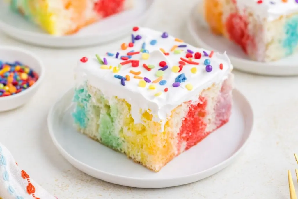 Piece of colorful jello poke cake on a plate. 