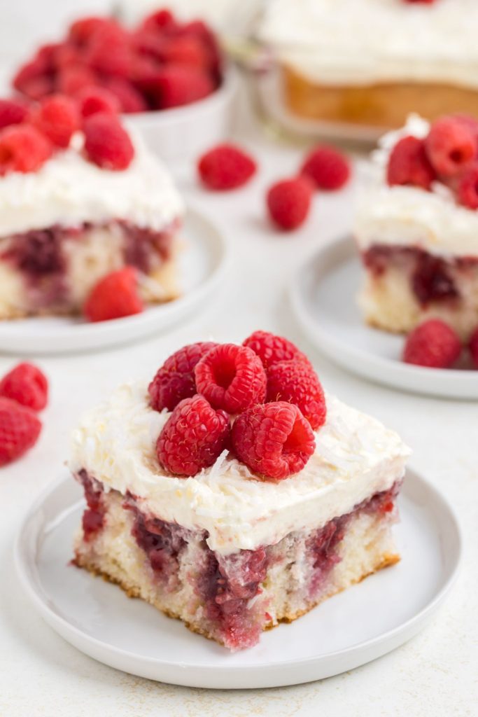 Slice of coconut raspberry poke cake with raspberry preserves. 