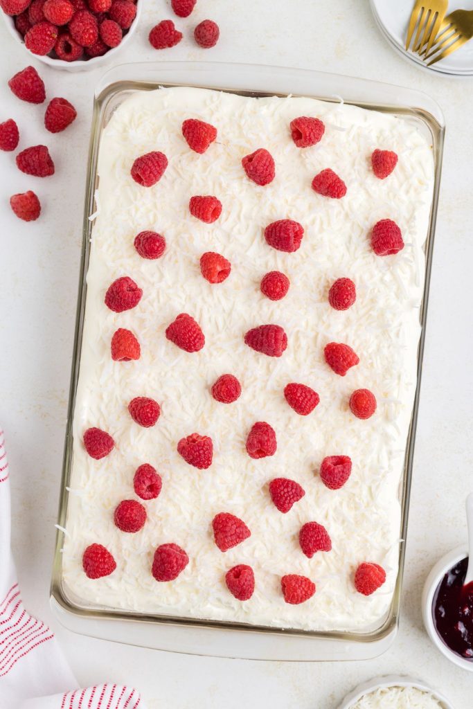Poke cake with raspberry filling and coconut cream frosting. 