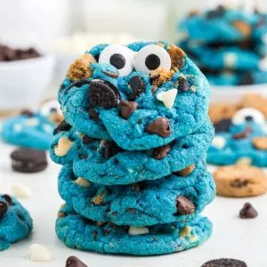 Pile of bright blue Cookie Monster cookies with cookie chunks.