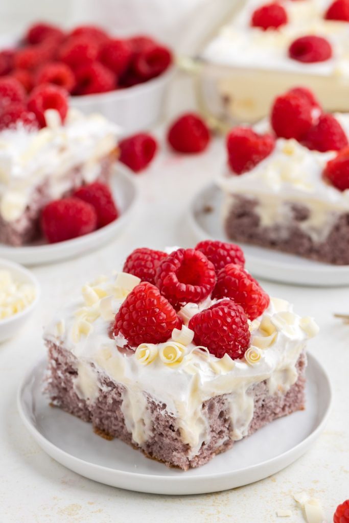 Slice of raspberry poke cake with white chocolate pudding filling.