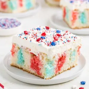 4th of July poke cake with white chocolate whipped topping on a plate.
