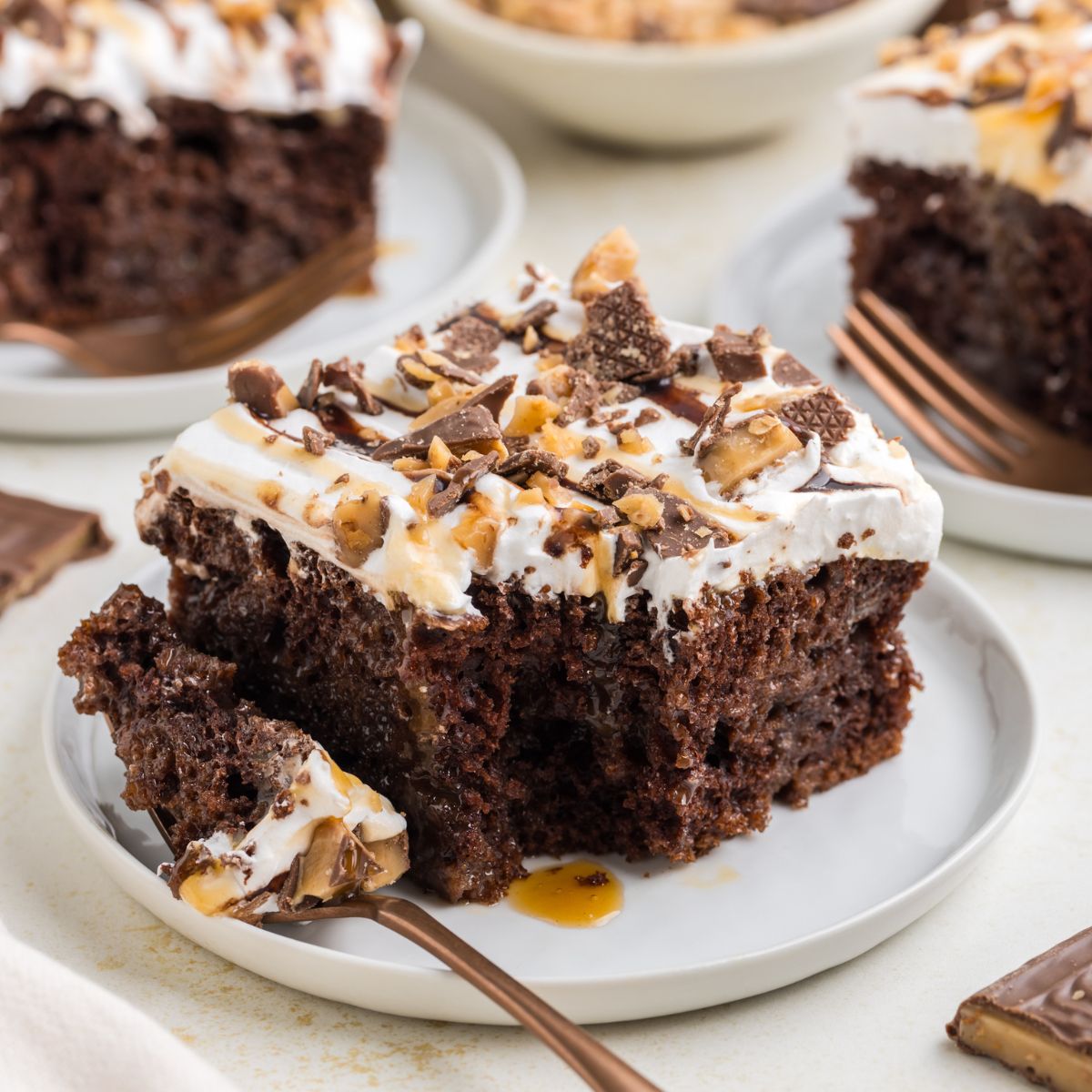 Slice of Heath bar poke cake on a plate with forkful of cake missing.