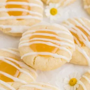 Lemon curd thumbprint cookies with lemon glaze in a pile.