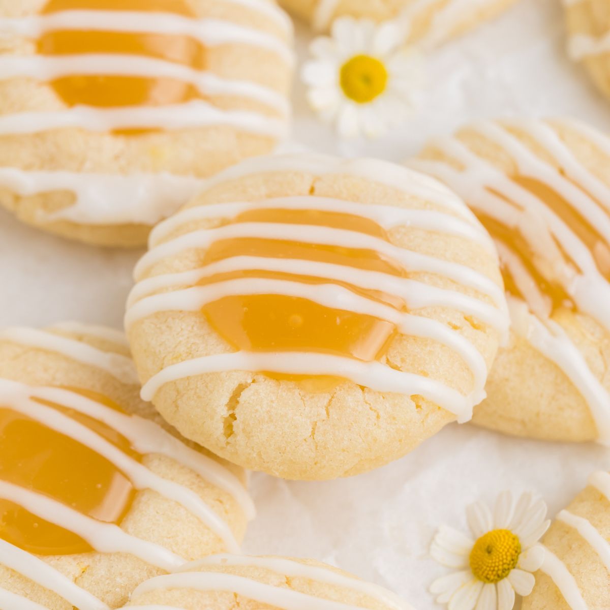 Lemon curd thumbprint cookies with lemon glaze in a pile.