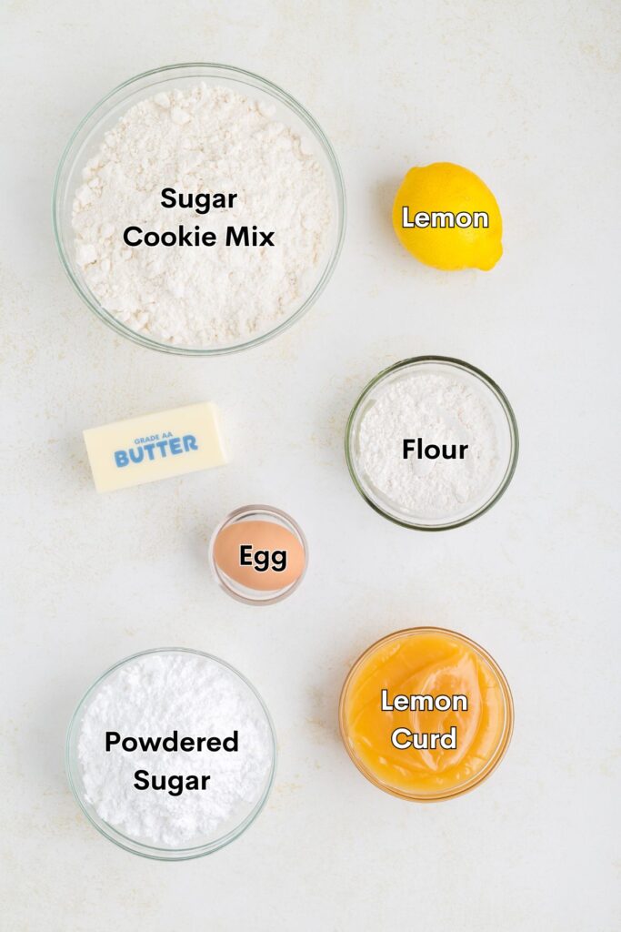 Ingredients such as cookie mix, lemon, flour, egg, butter, powdered sugar, and lemon curd displayed on the counter.