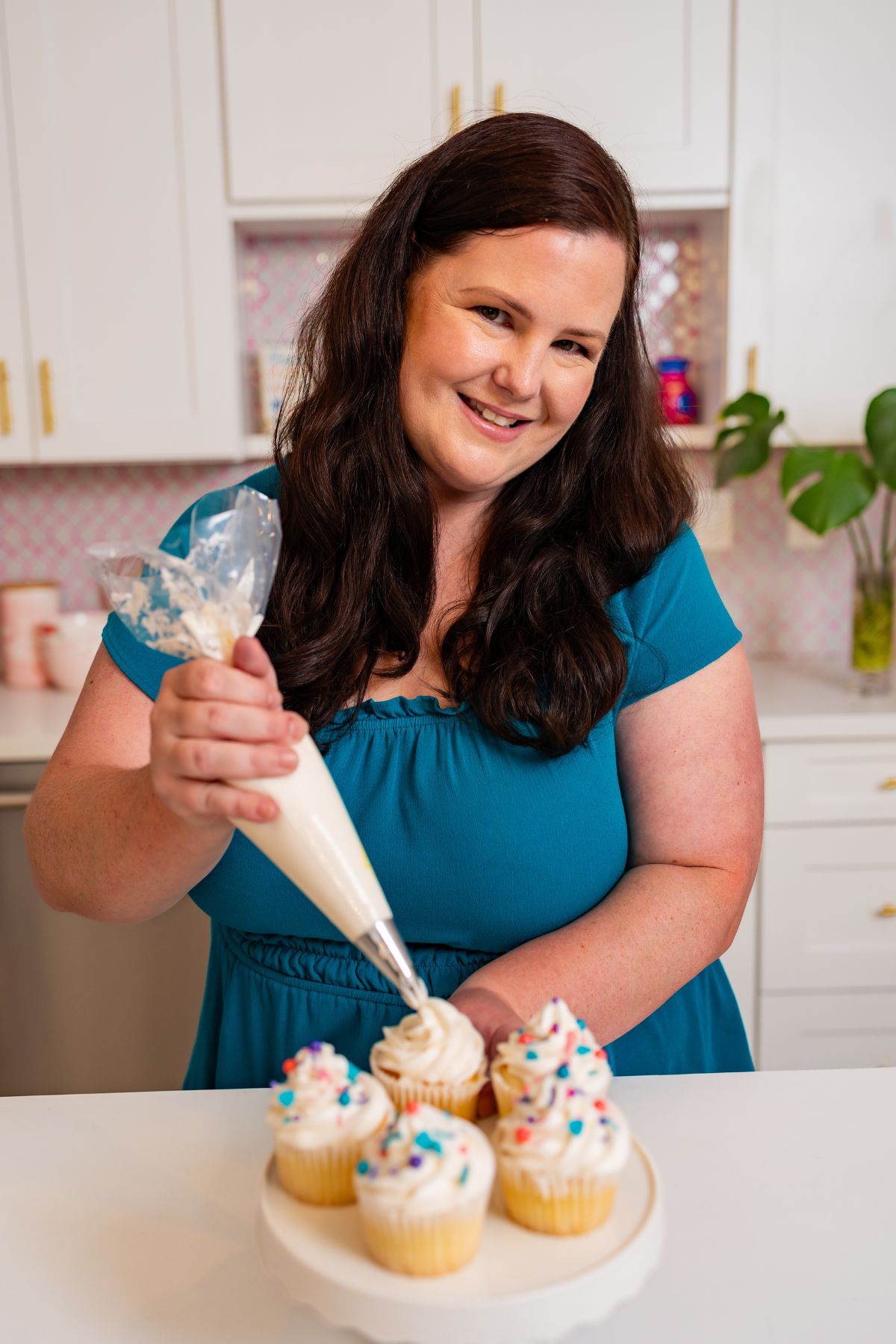 Mandy the creator of Semi Homemade Kitchen piping vanilla frosting onto cupcakes.