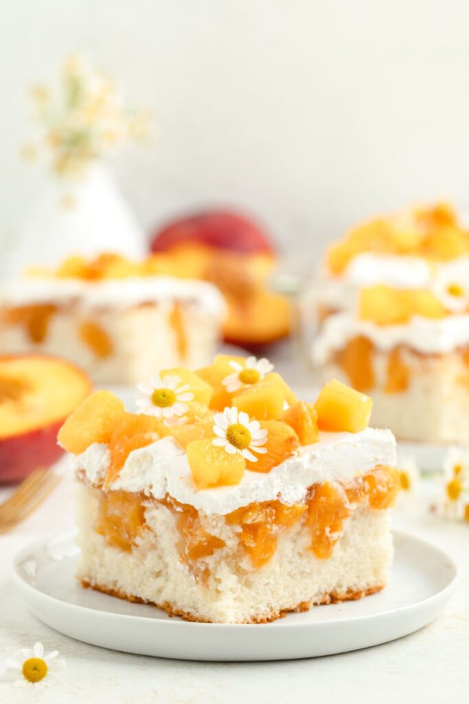 Slice of peach poke cake with pie filling and Cool Whip.