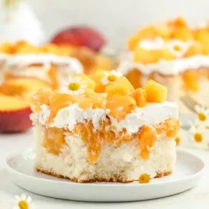 Peaches and cream poke cake with fresh peach topping.