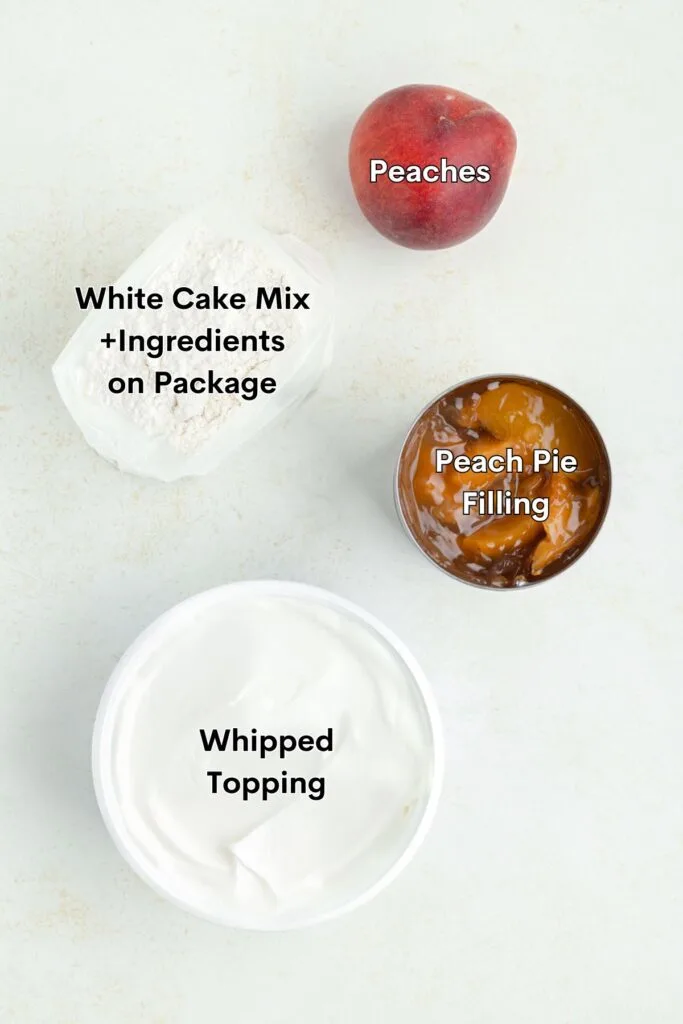 Ingredients such as white cake mix, peach pie filling, whipped topping and fresh peaches displayed on the counter.