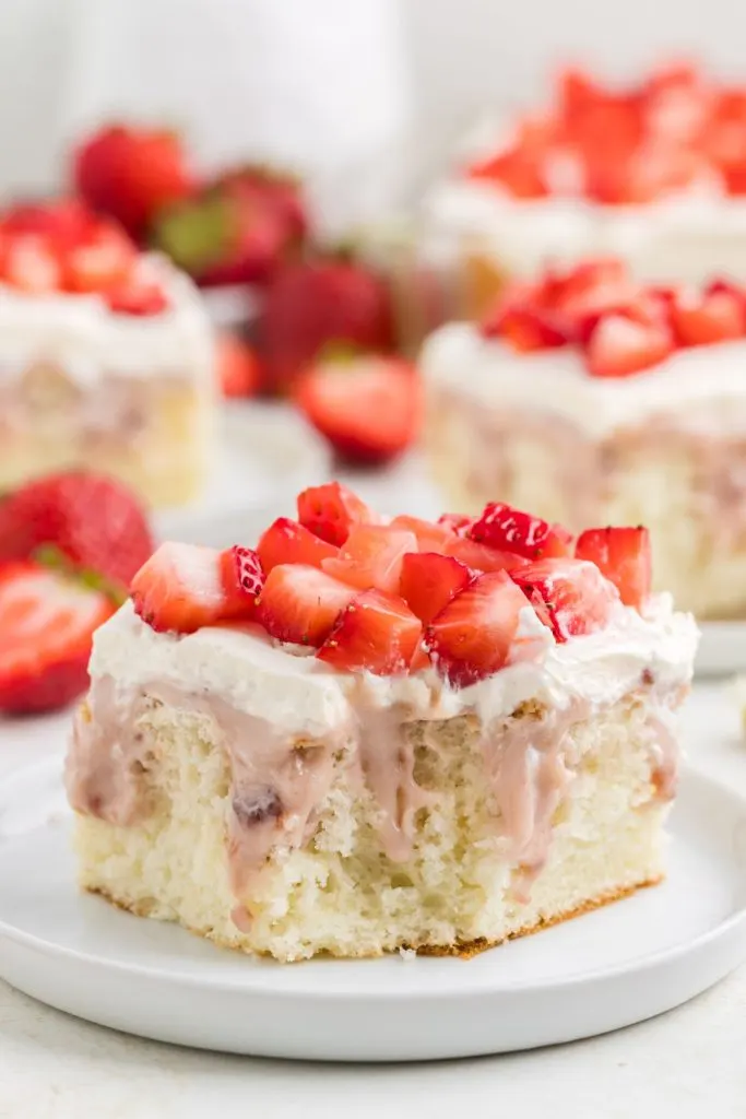 Slice of strawberry cheesecake cake with bite missing.