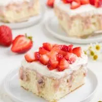 Slice of strawberry cheesecake poke cake with fresh strawberries.