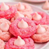 Pink strawberry cake mix cookies with Strawberry chocolate kisses piled on a plate.