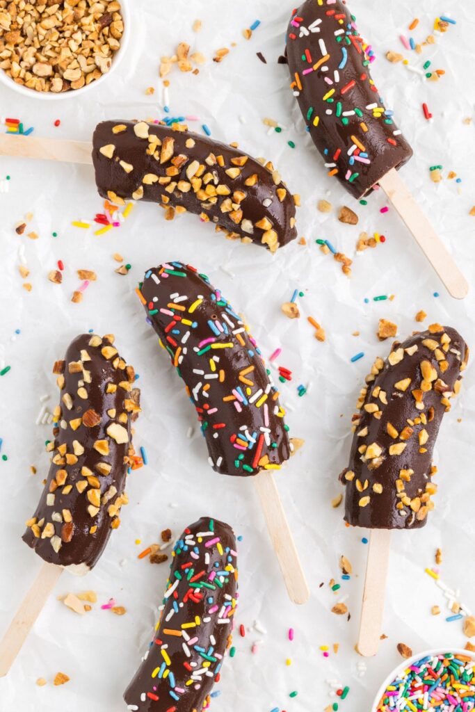 Frozen chocolate covered bananas with sprinkles and nuts.