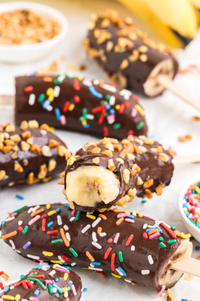 Chocolate covered banana popsicle with bite taken out of it.