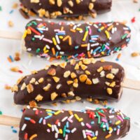 Chocolate covered frozen bananas with nuts and sprinkles.