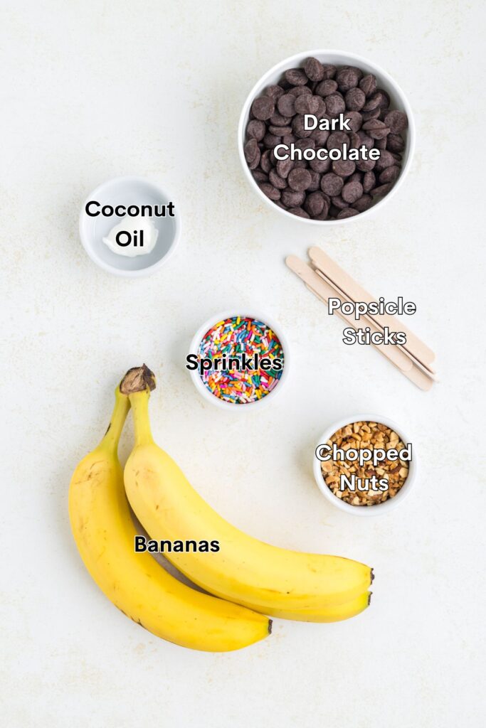 Ingredients such as bananas, chocolate, coconut oil, chopped nuts, and sprinkles arranged on the counter.