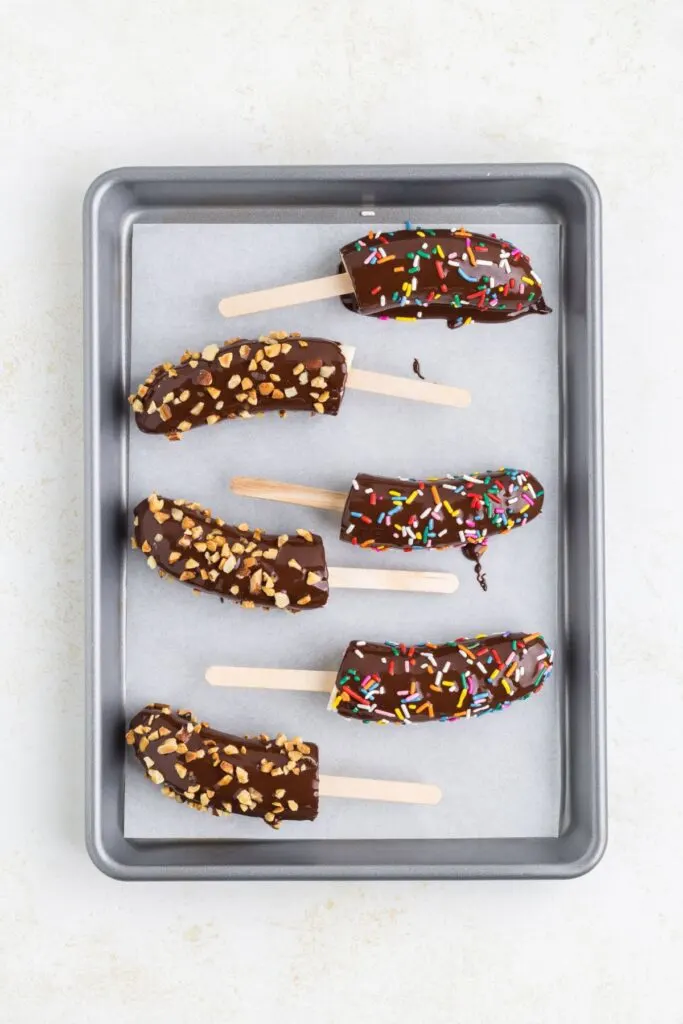 Chocolate dipped bananas on a parchment paper lined tray.