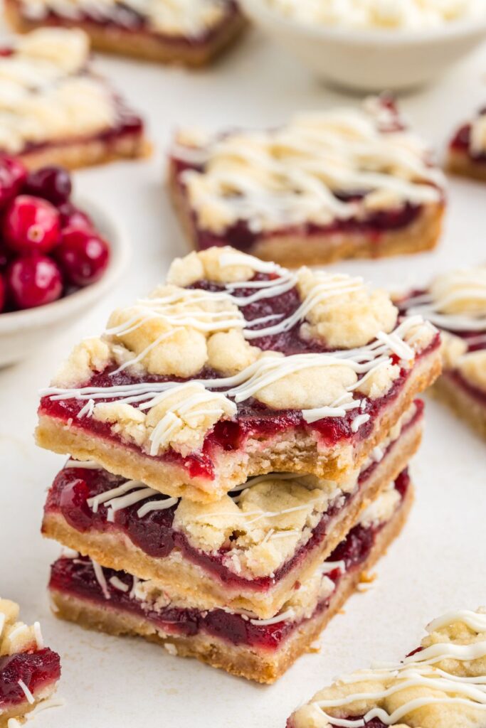 Stack of cranberry crumb bars with white chocolate drizzle.