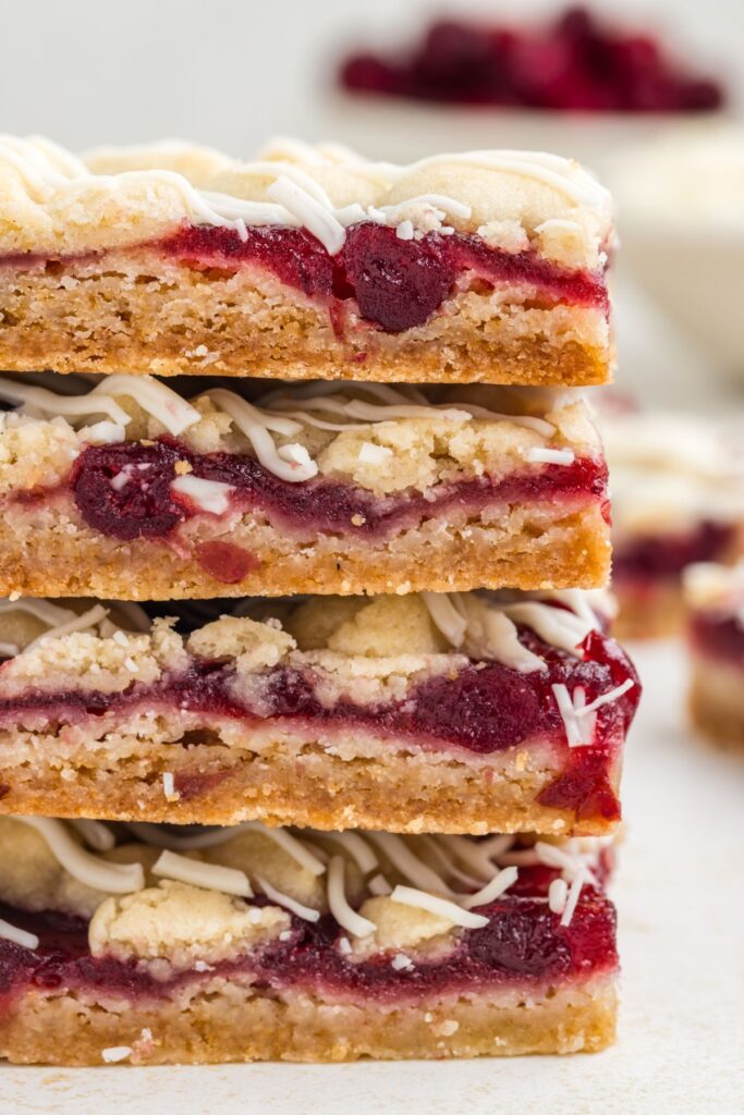 Four white chocolate cranberry crumb bars stacked.