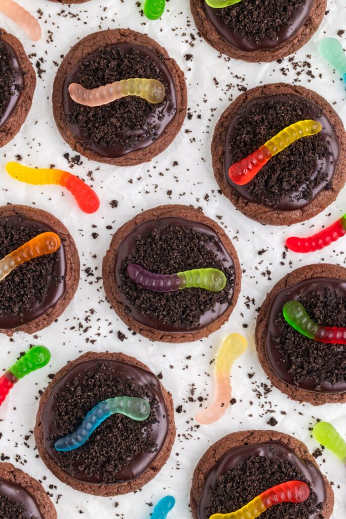 Chocolate cookies decorated with crushed cookies and gummy worms.