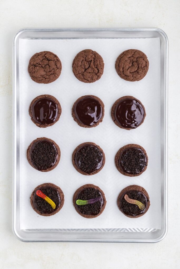 Dirt worm cookies being decorated on a cookie sheet.