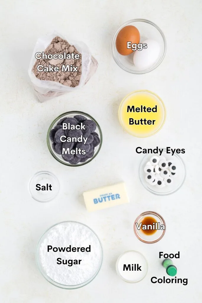 Ingredients such as chocolate cake mix, butter, egg, powdered sugar, food coloring, candy melts and candy eyes displayed on the counter.