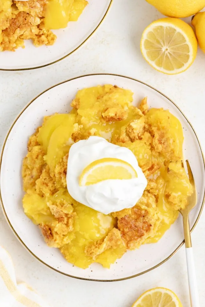  3 ingredient lemon dump cake on a plate with whipped cream