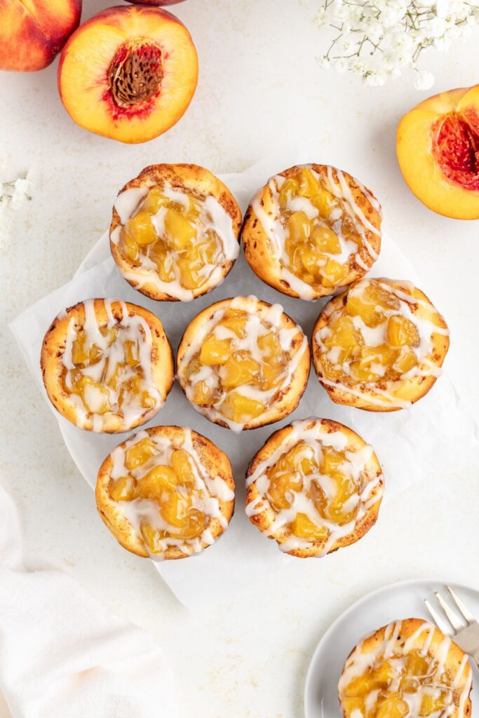 Mini peach pies with vanilla glaze on a plate.