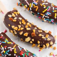Chocolate banana popsicles with chopped nuts and rainbow sprinkles.