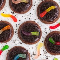 Chocolate cookies decorated with crushed cookies and gummy worms.