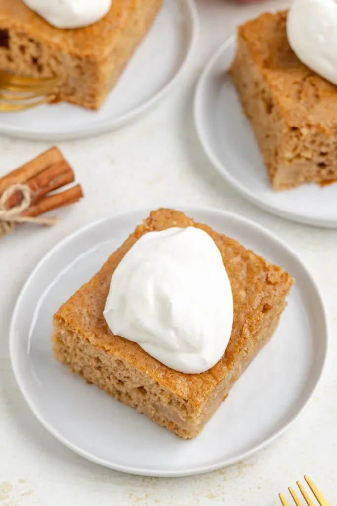 Apple cake made with 3 ingredients topped with whipped cream.