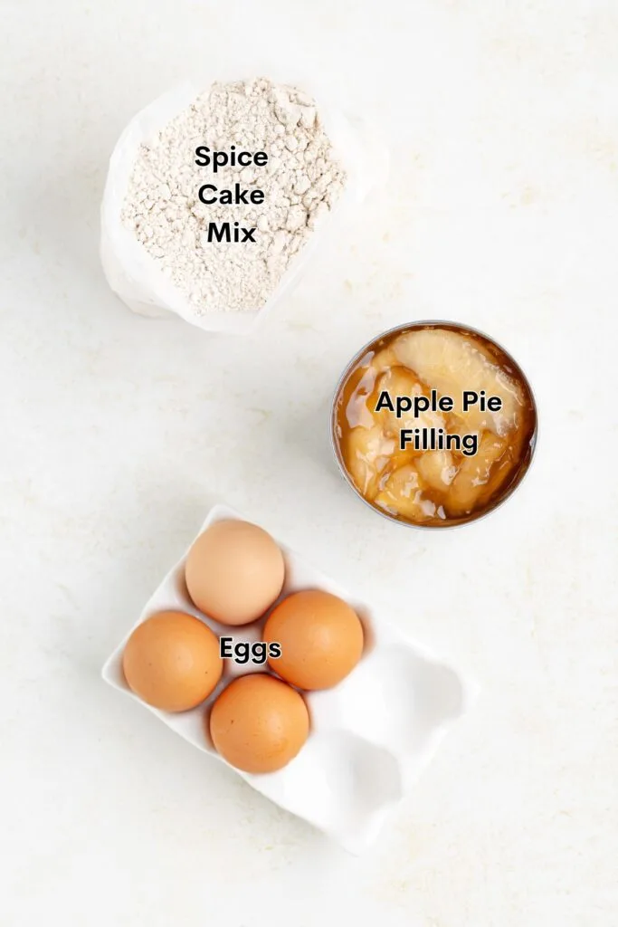 Ingredients such as spice cake mix, eggs, and apple pie filling on the counter.