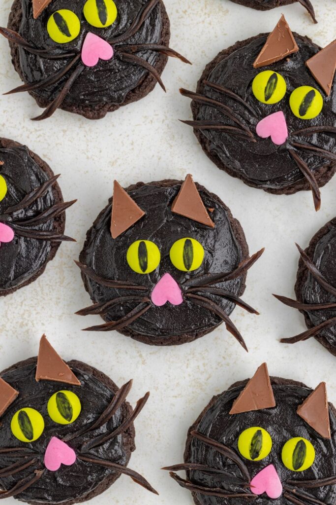 Chocolate black cat cookies with green eyes.