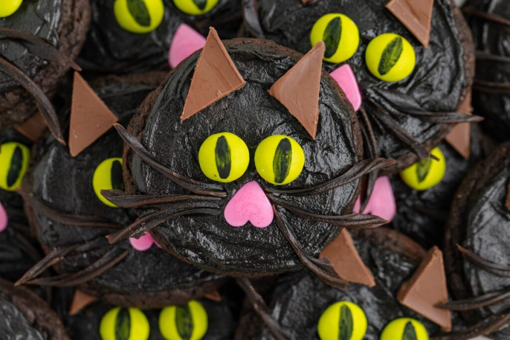 Pile of black cat cookies with candy faces.