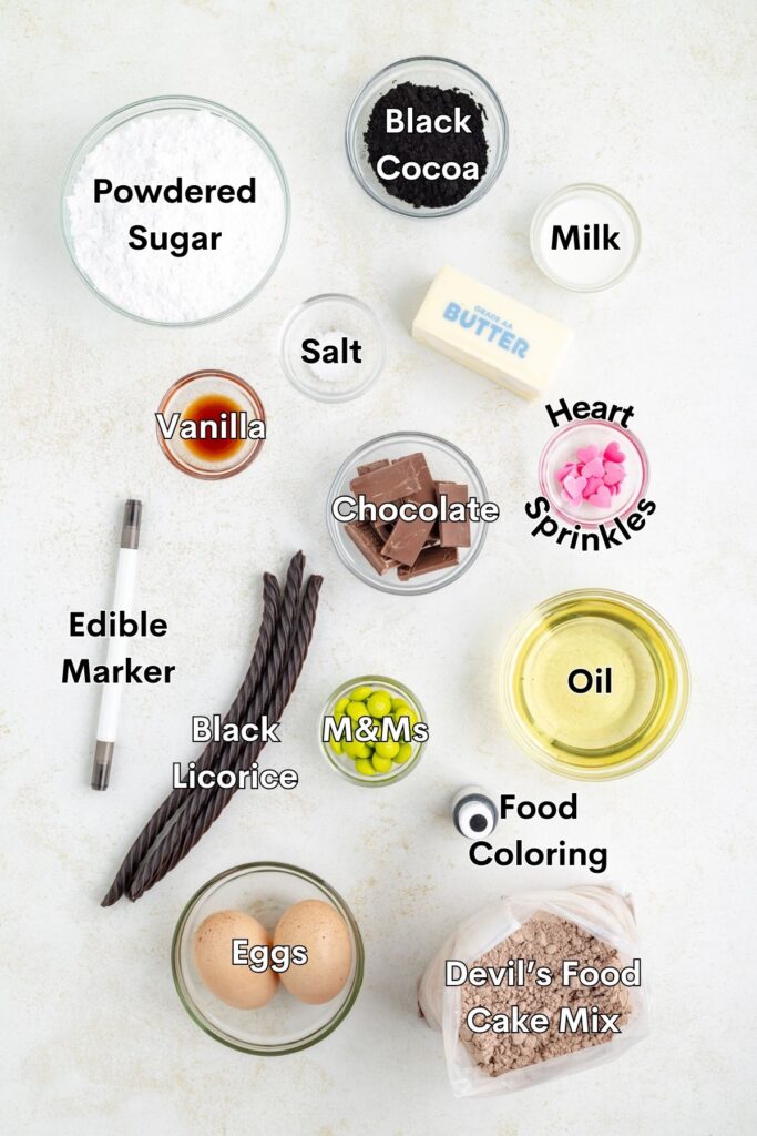 Ingredients such as cake mix, eggs, oil, powdered sugar, butter, black cocoa, and candy arranged on the counter.