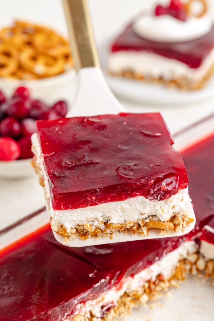 Slice of cranberry pretzel salad being removed from the pan.