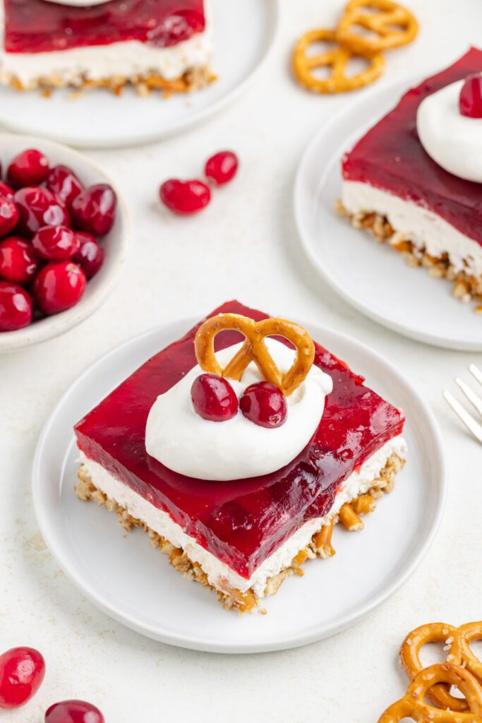 Slice of cranberry pretzel salad topped with whipped cream.