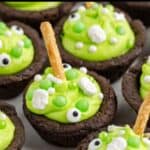 Chocolate cookie cups with green frosting, candy eyeballs, bone candies, and pretzel sticks as spooky cauldron treats.