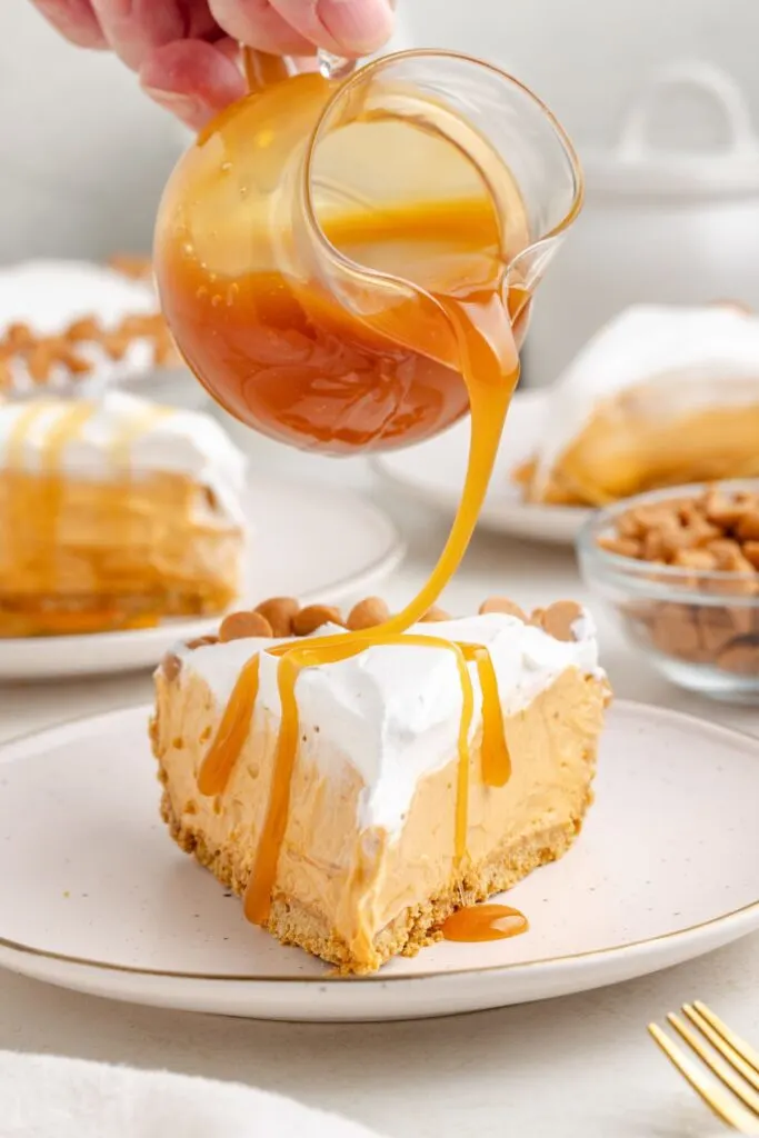 Butterscotch sauce being drizzled over a slice of no bake pie.