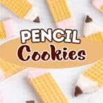 Wafer cookies decorated as pencils with icing and chocolate tips, arranged on a notebook with a sharpener.