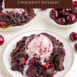Chocolate cherry dump cake with melting ice cream on a plate, fresh cherries around, another serving behind.