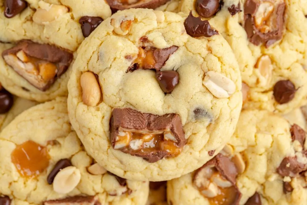 Pile of Snickers cookies with caramels and chocolate chips.