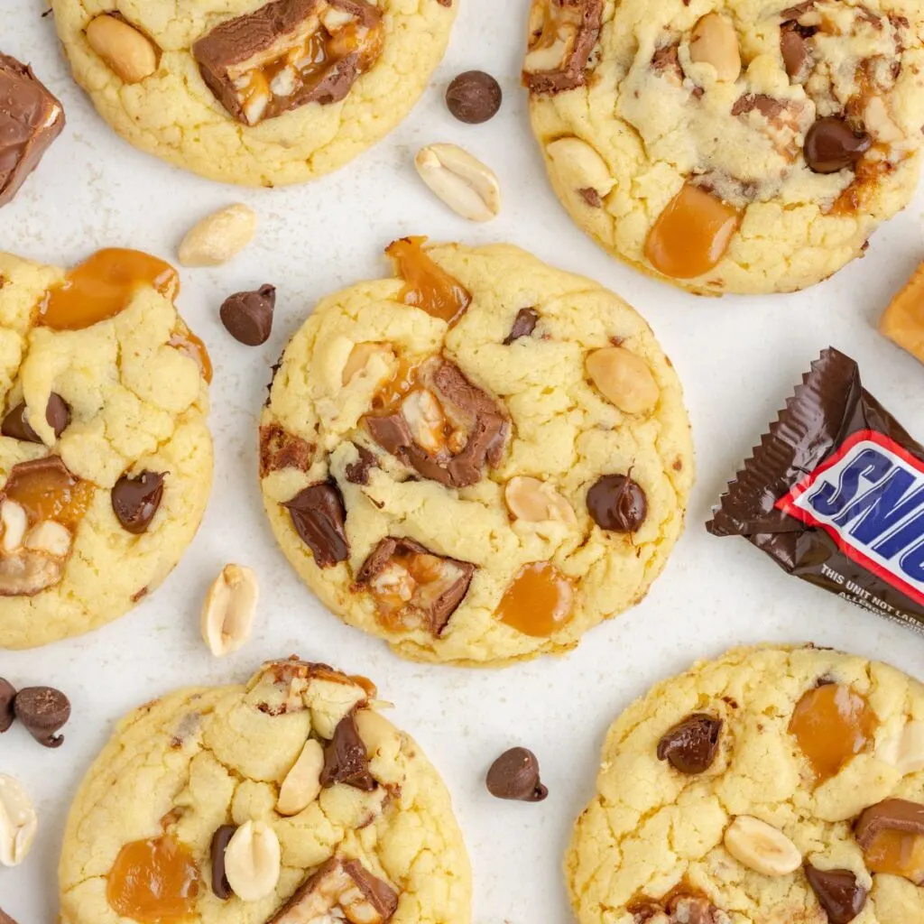 Cake mix Snickers cookies with gooey caramel, chocolate and peanuts.