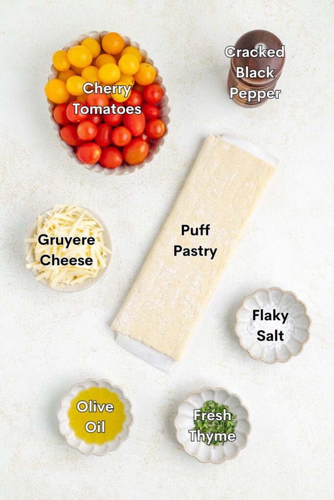 Ingredients such as puff pastry, cherry tomatoes, gruyere cheese, olive oil, thyme, salt, and pepper.