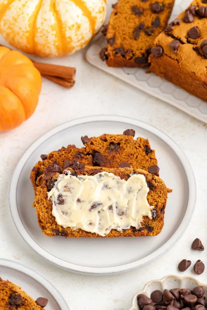 Chocolate chip pumpkin bread spread with butter.