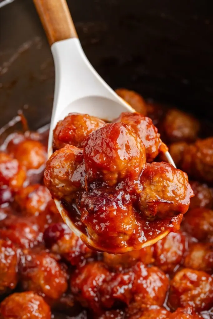 Spoonful of 3-ingredient cranberry meatballs being removed from the crockpot.