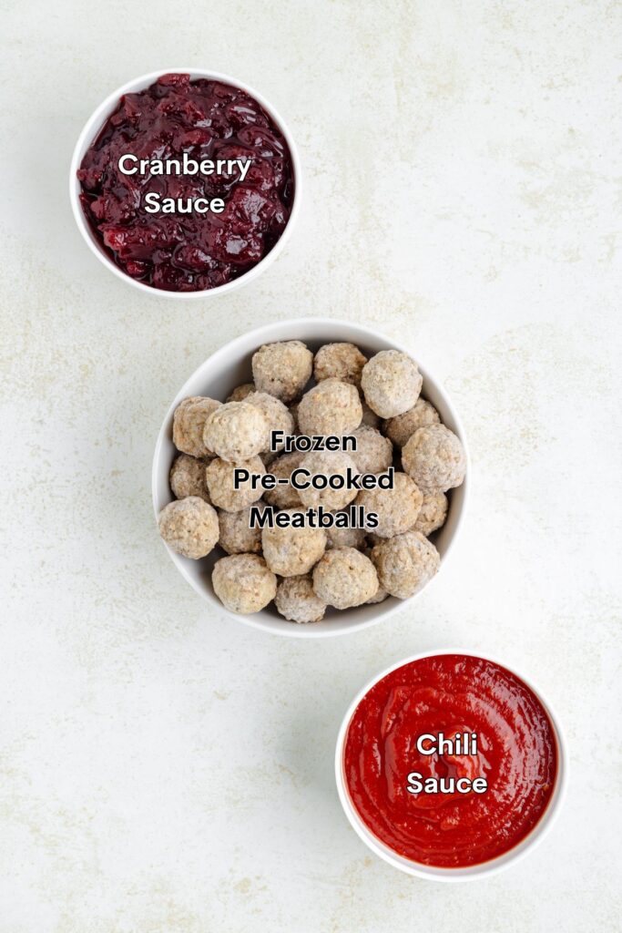 Frozen meatballs, cranberry sauce, and chili sauce in bowls on the counter.