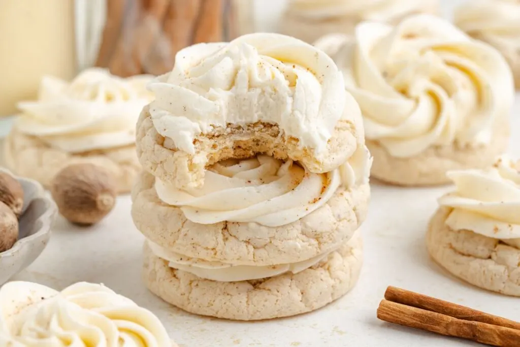 Stack of three eggnog cookies with piped buttercream with bite missing from the top cookie.